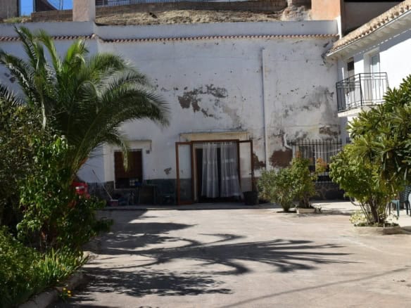 Cave house exterior in Cuevas del Campo, Granada with lush greenery and outdoor space.