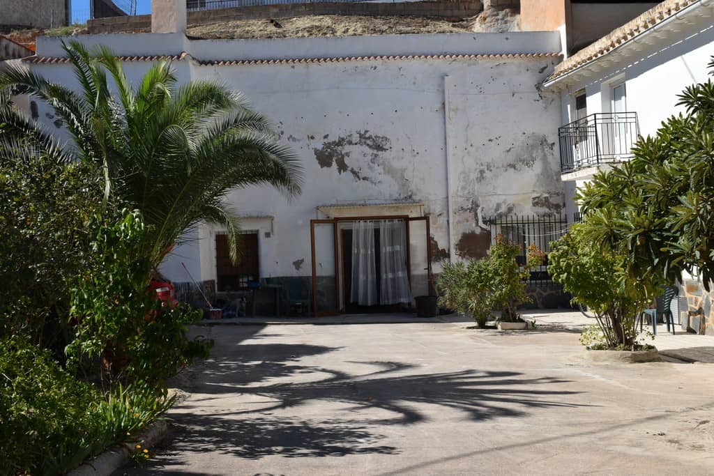 Cave house exterior in Cuevas del Campo, Granada with lush greenery and outdoor space.