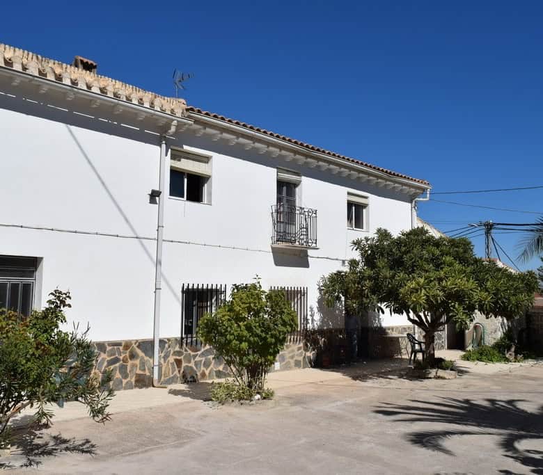 Cave house in Cuevas del Campo, Granada with white exterior and lush garden.