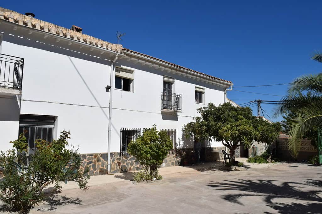 Cave house in Cuevas del Campo, Granada with white exterior and lush garden.