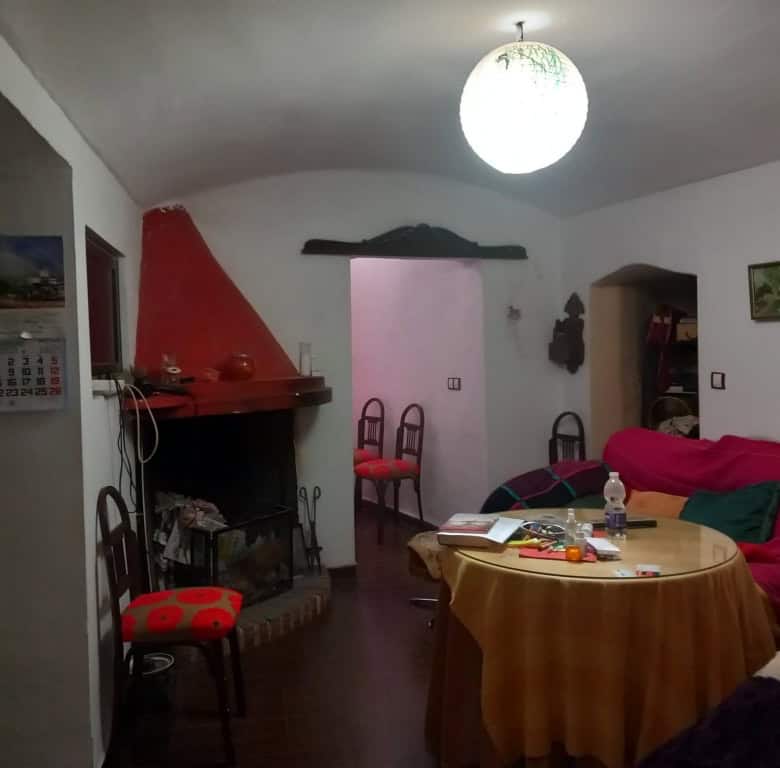Interior of traditional cave house in Cuevas del Campo, Granada, with fireplace and rustic decor.