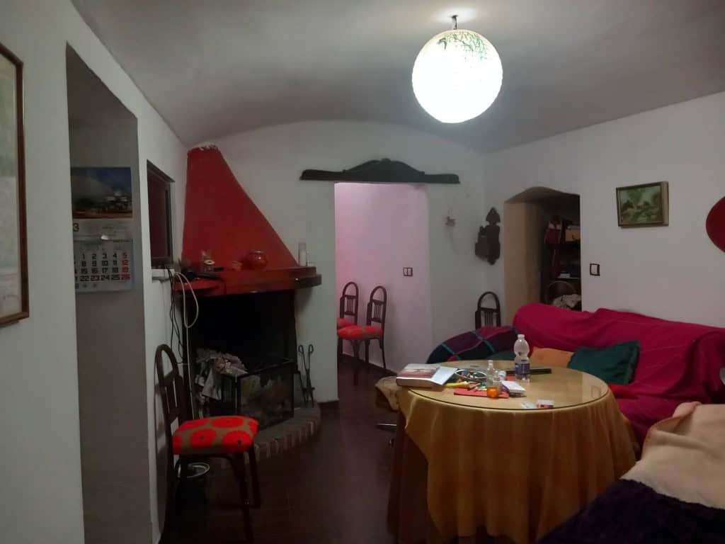 Interior of traditional cave house in Cuevas del Campo, Granada, with fireplace and rustic decor.