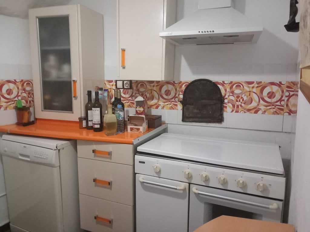 Cave house kitchen with modern appliances and colorful tile backsplash in Cuevas del Campo, Granada.