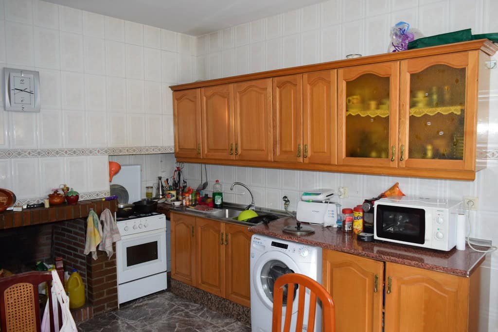 Traditional cave house kitchen with wooden cabinets and modern appliances in Granada.