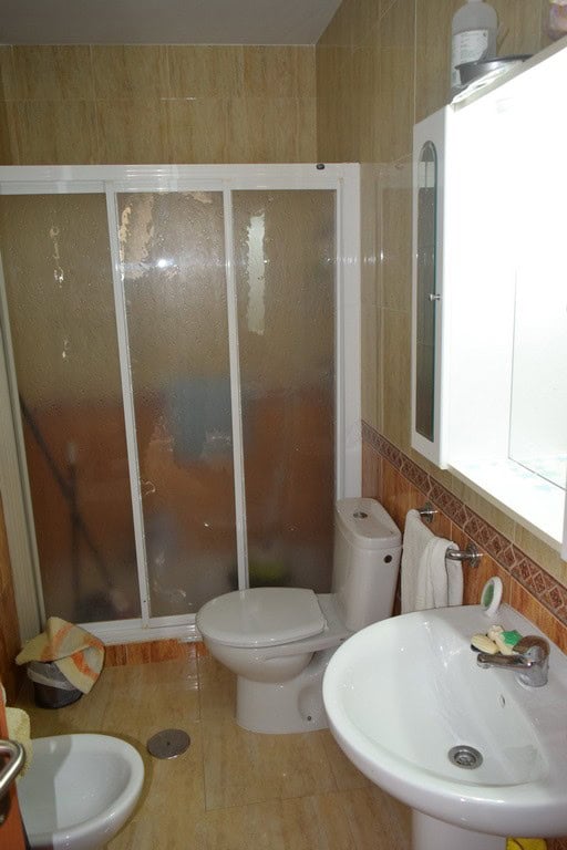 Cozy bathroom inside a cave house in Cuevas del Campo, Granada, featuring a shower, toilet, and sink.