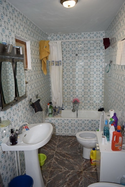 Cave house bathroom with vintage decor, bathtub, sink, and toiletries in Cuevas del Campo, Granada.