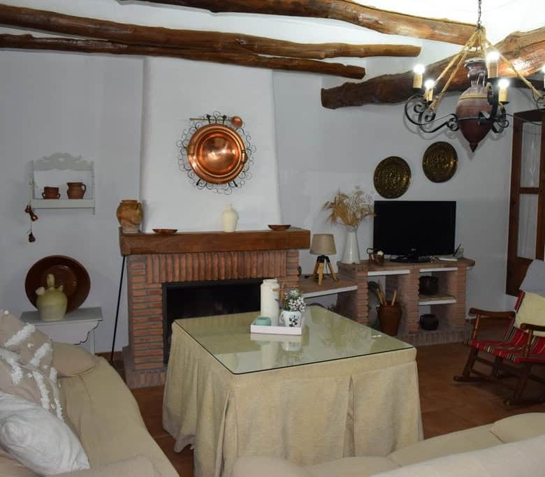 Charming cave house interior with rustic wooden beams, cozy fireplace, and traditional decor in Bena.