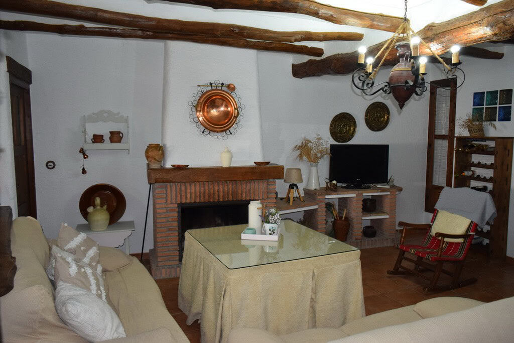 Charming cave house interior with rustic wooden beams, cozy fireplace, and traditional decor in Bena.