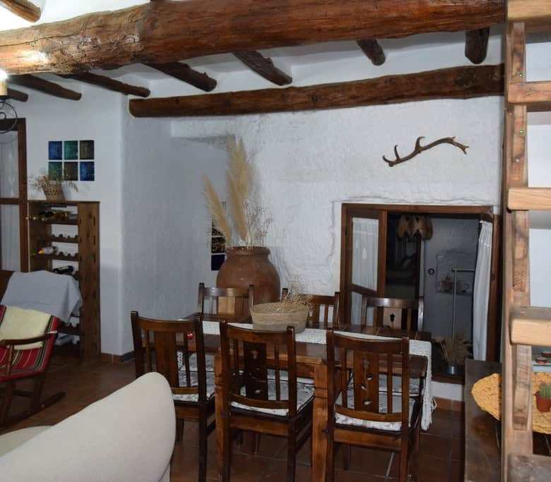 Charming cave house interior in Benamaurel, Granada, featuring rustic wooden beams and traditional d.