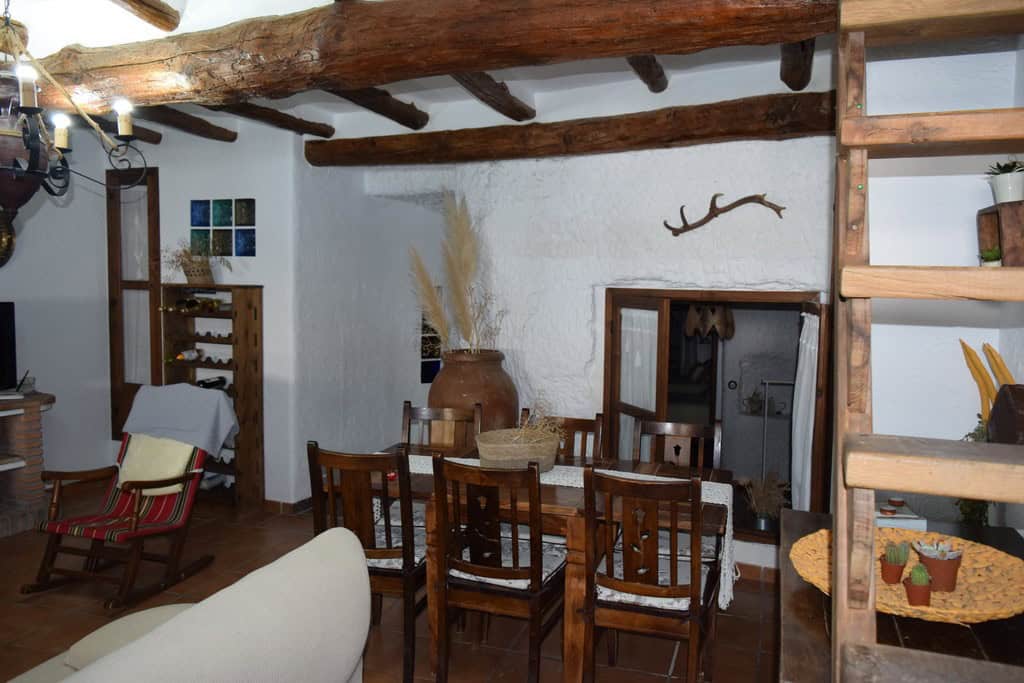 Charming cave house interior in Benamaurel, Granada, featuring rustic wooden beams and traditional d.