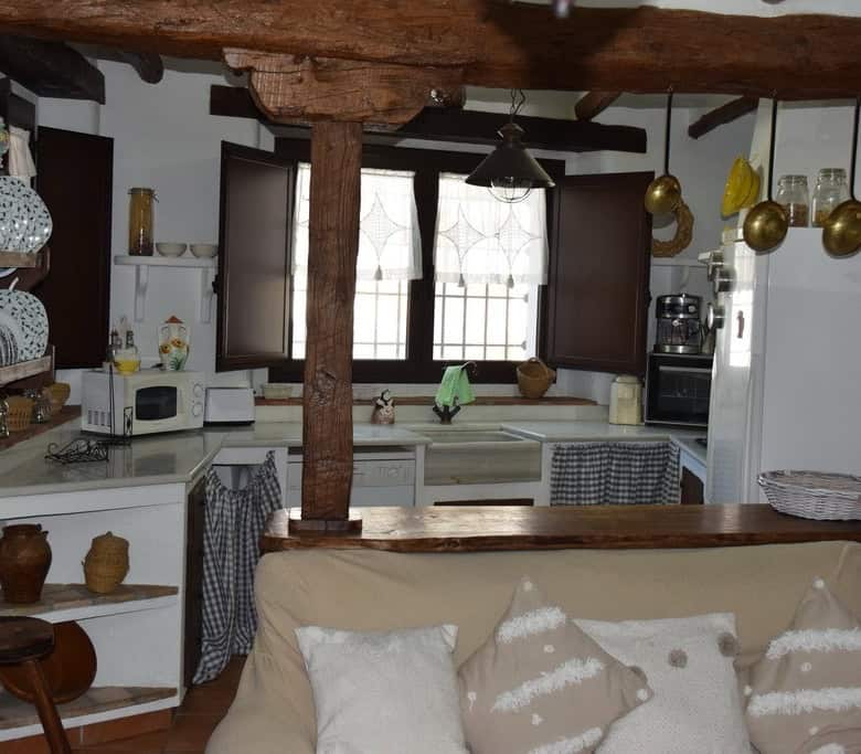 Charming cave house interior in Benamaurel, Granada, featuring rustic wooden beams and traditional d.