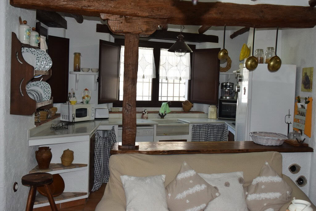 Charming cave house interior in Benamaurel, Granada, featuring rustic wooden beams and traditional d.