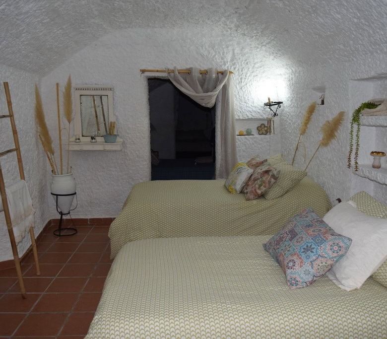 Charming cave house interior with rustic decor in Benamaurel, Granada, featuring comfortable beds an.