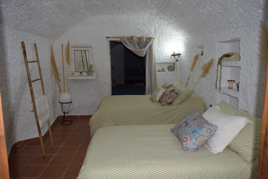 Charming cave house interior with rustic decor in Benamaurel, Granada, featuring comfortable beds an.