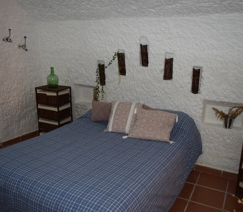 Charming cave house bedroom in Benamaurel, Granada with rustic decor and unique interior design.