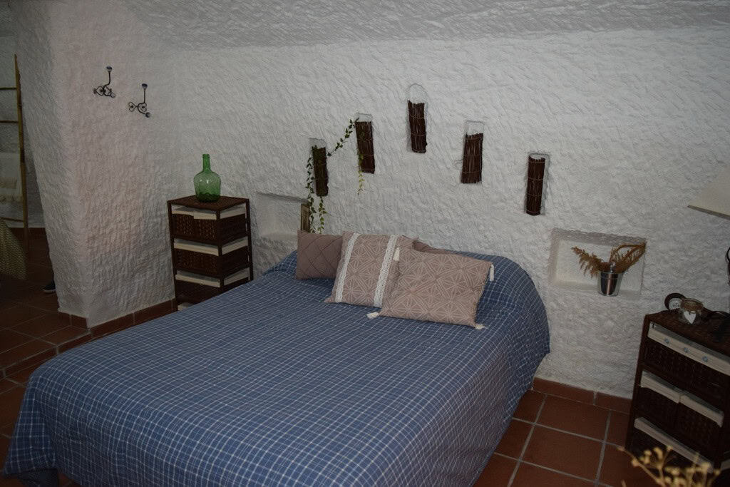 Charming cave house bedroom in Benamaurel, Granada with rustic decor and unique interior design.