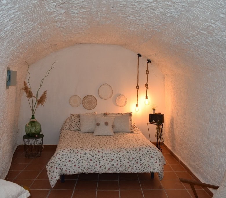 Unique cave house interior in Benamaurel, Granada with cozy bedroom and rustic decor.