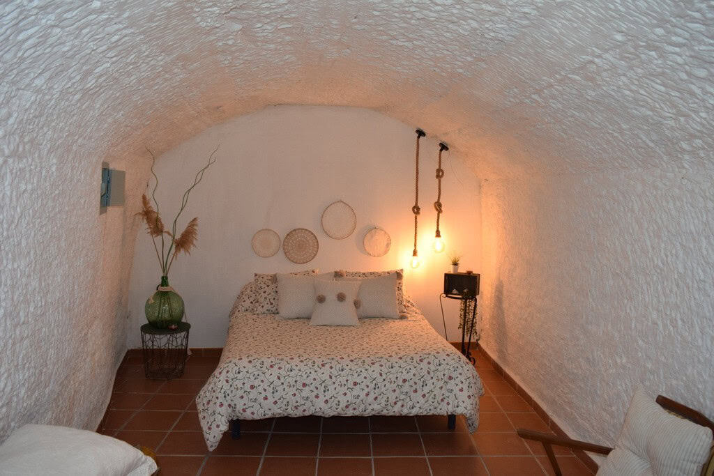 Unique cave house interior in Benamaurel, Granada with cozy bedroom and rustic decor.