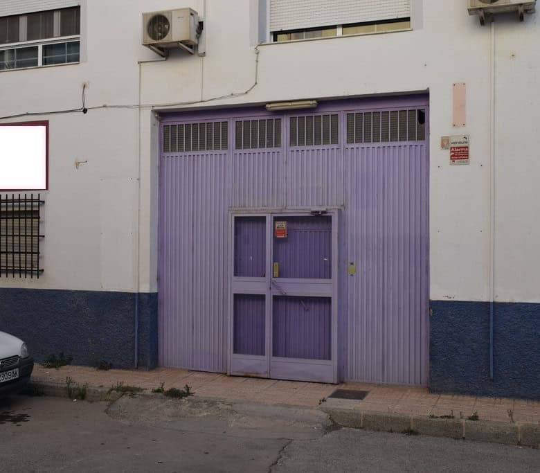 Garage door in Baza, Granada, Spain, with purple metal doors and surrounding white building facade.