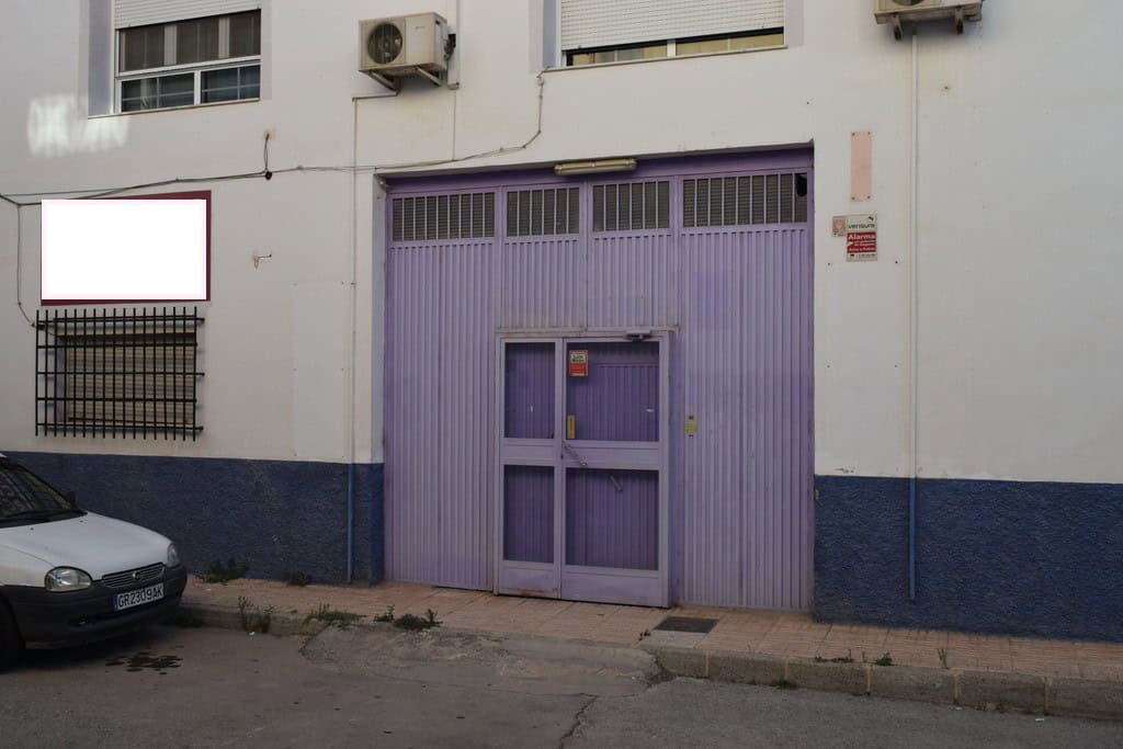 Garage door in Baza, Granada, Spain, with purple metal doors and surrounding white building facade.