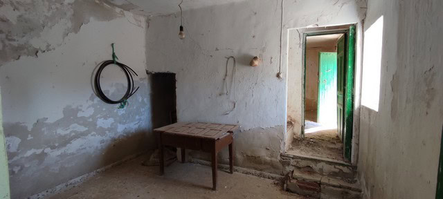 Traditional rural property interior in Valcabra, Granada, with unfinished walls and rustic features.