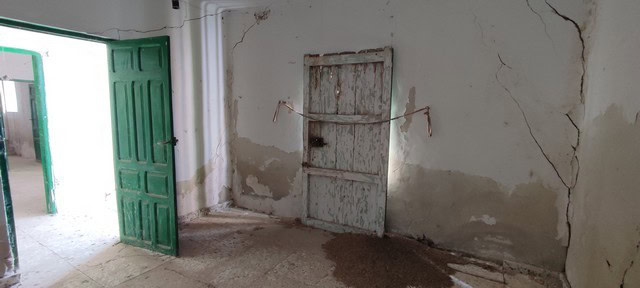 Interior of a rustic rural property in Valcabra, Granada, showing aged walls and a simple door.