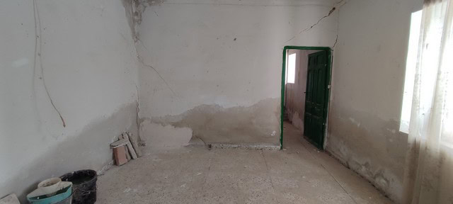 Interior view of a rustic rural property in Valcabra, Granada, showing aged walls and an open doorwa.