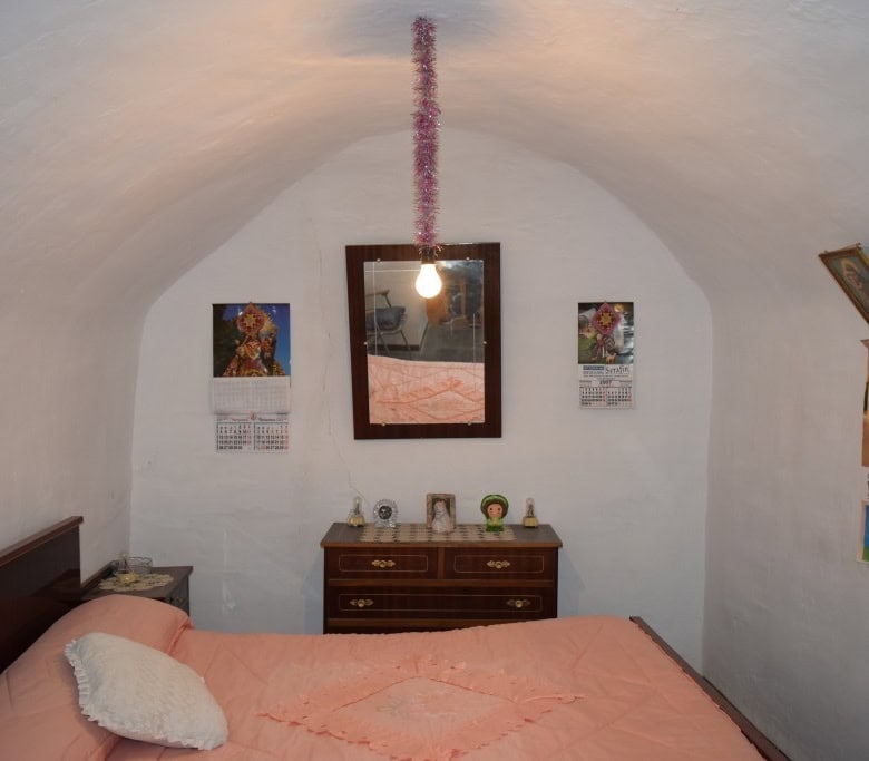 Cozy cave house bedroom with white arched ceiling in Benamaurel, Granada, featuring simple decor and.