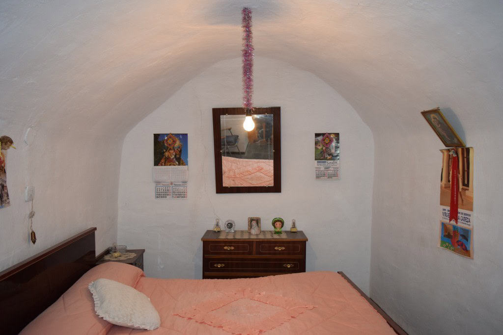 Cozy cave house bedroom with white arched ceiling in Benamaurel, Granada, featuring simple decor and.