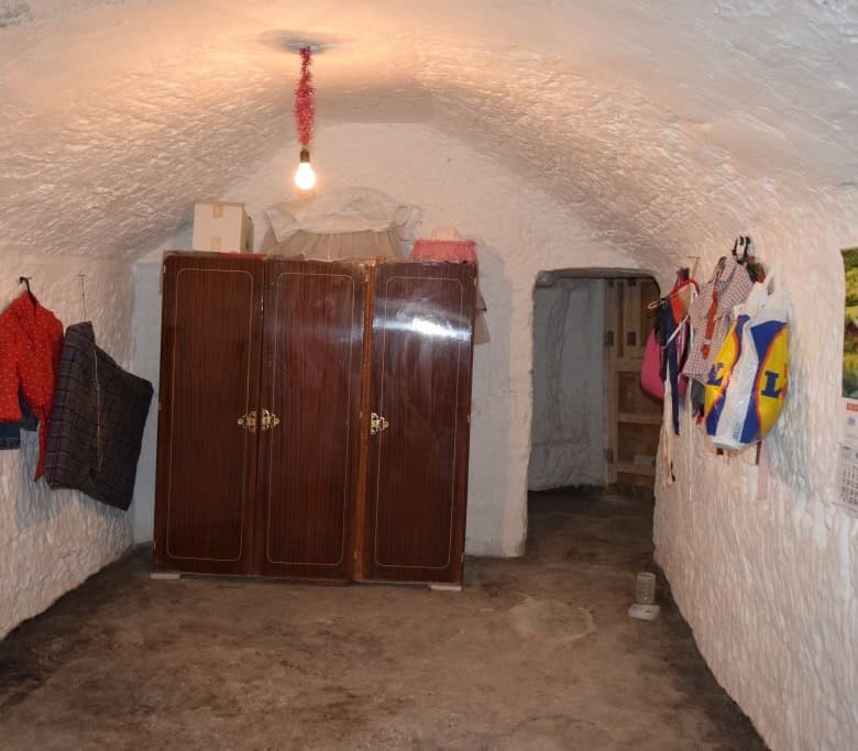 Cave house interior with rustic furniture and hanging textiles in Benamaurel, Granada. Unique underg.