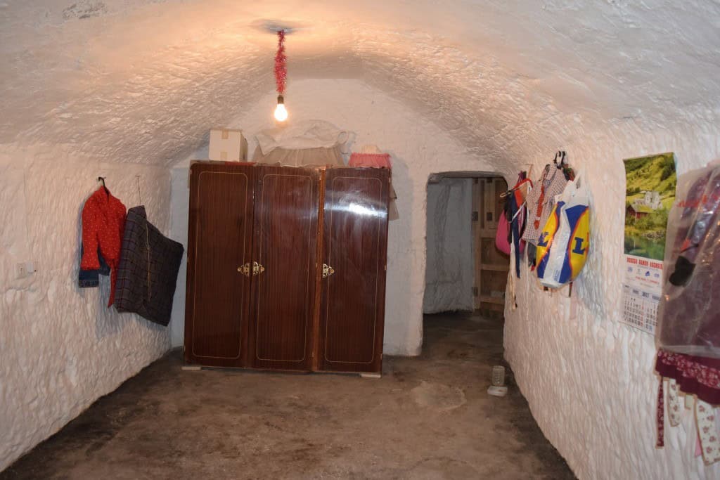 Cave house interior with rustic furniture and hanging textiles in Benamaurel, Granada. Unique underg.