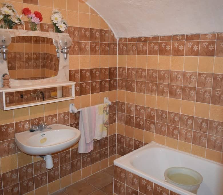 Cozy cave house bathroom with vintage tiles, sink, and bathtub in Benamaurel, Granada.