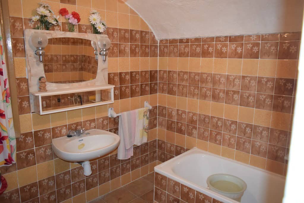 Cozy cave house bathroom with vintage tiles, sink, and bathtub in Benamaurel, Granada.