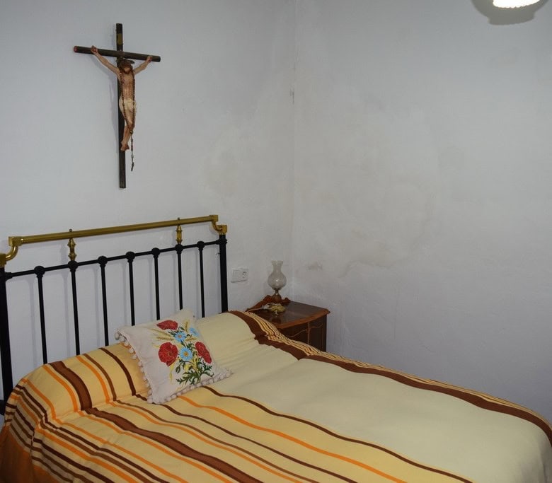Cozy bedroom in a village property in Caniles, Granada, featuring a simple bed with colorful striped.