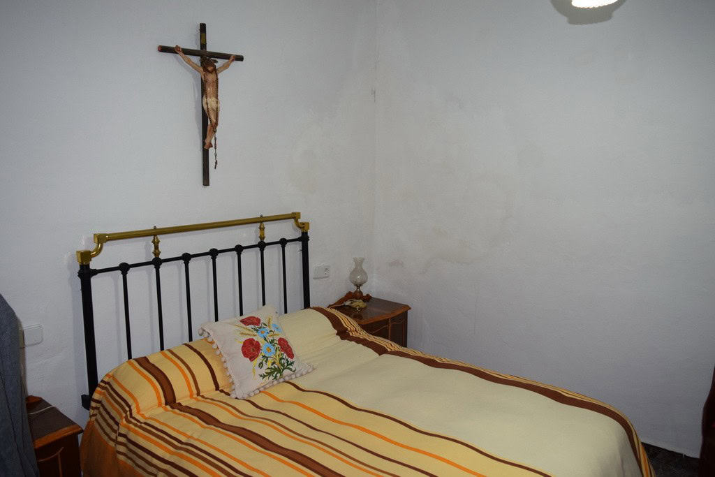 Cozy bedroom in a village property in Caniles, Granada, featuring a simple bed with colorful striped.