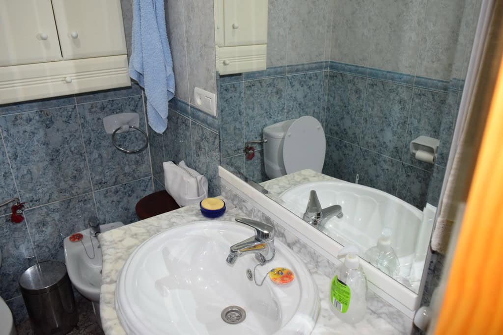Village property bathroom with sink, toilet, and mirror in Caniles, Granada.