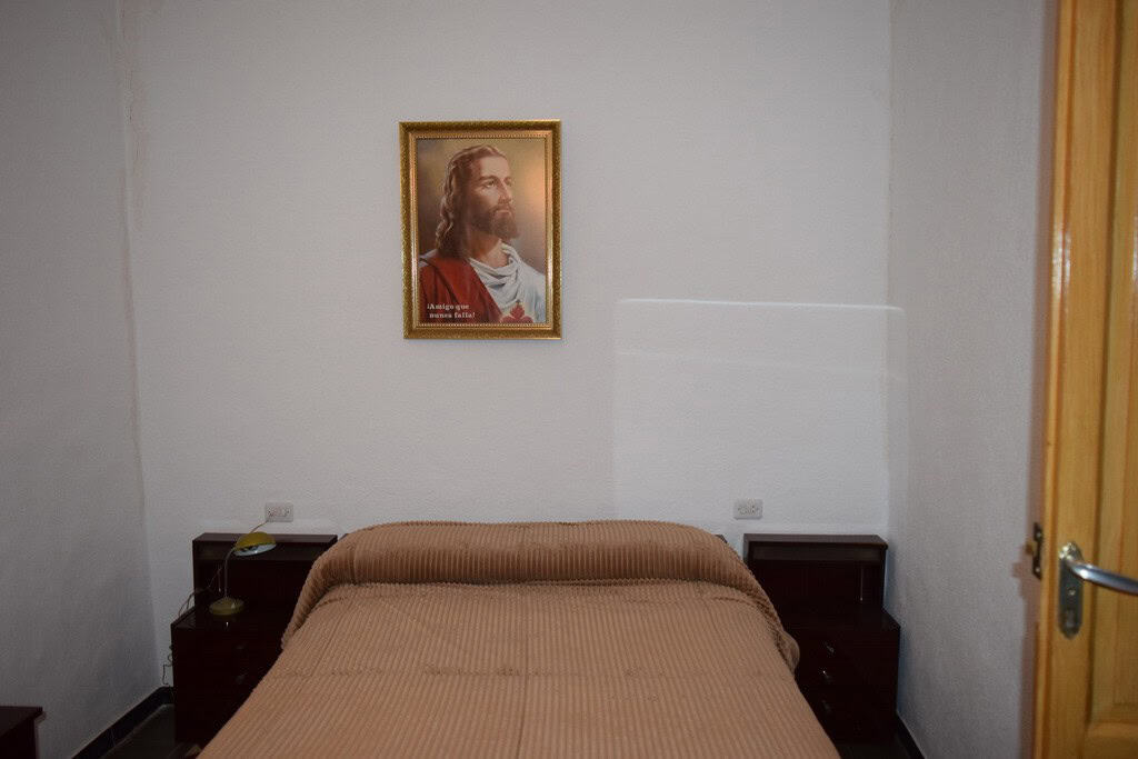 Charming village property in Caniles, Granada, featuring a cozy bedroom with religious artwork and s.