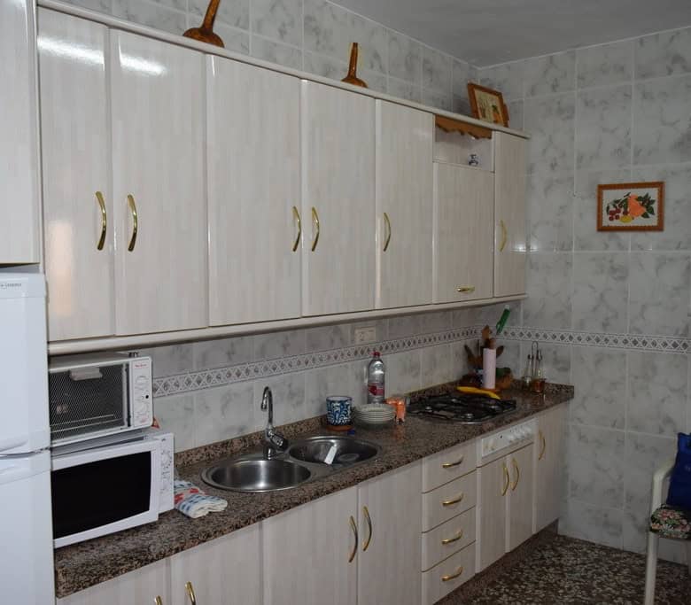 Charming kitchen in a village property located in Caniles, Granada, featuring white cabinets, a smal.