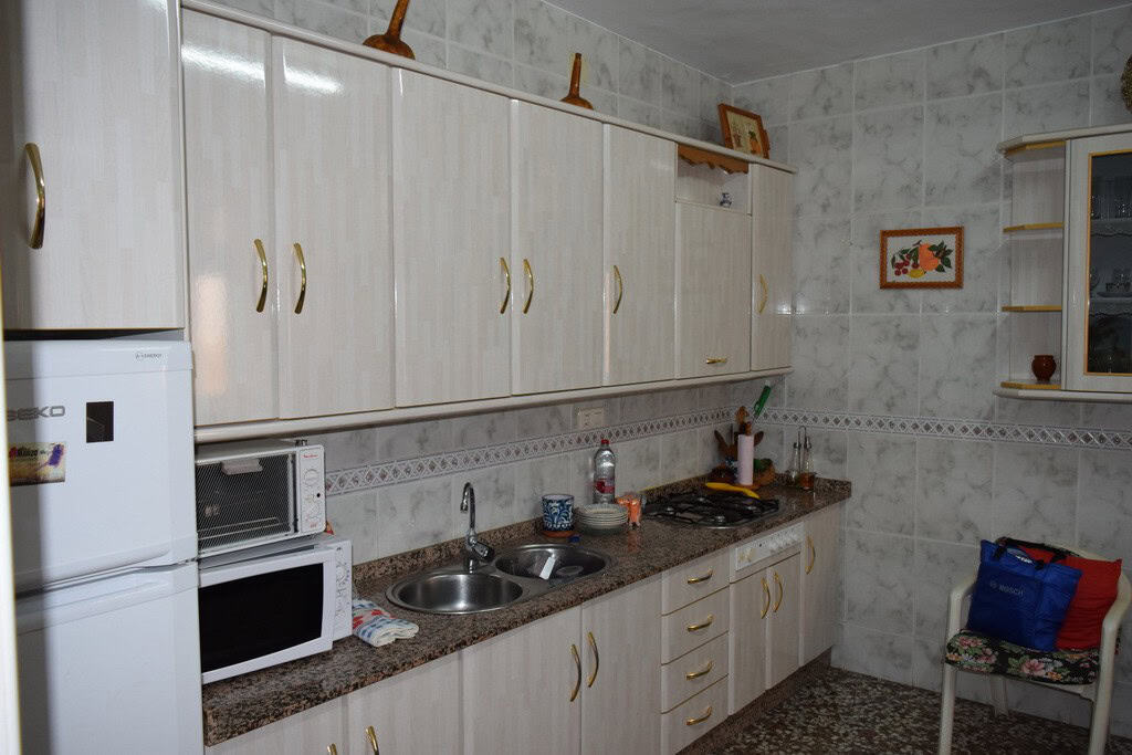 Charming kitchen in a village property located in Caniles, Granada, featuring white cabinets, a smal.