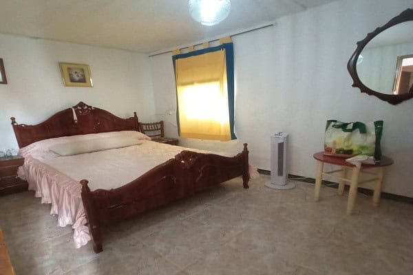 Charming bedroom in rural property in Don Pedro, Jaen, featuring a wooden bed and simple decor.
