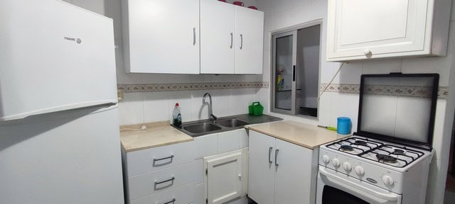 Kitchen with white cabinets, sink, and stove in Tijola, Almeria.