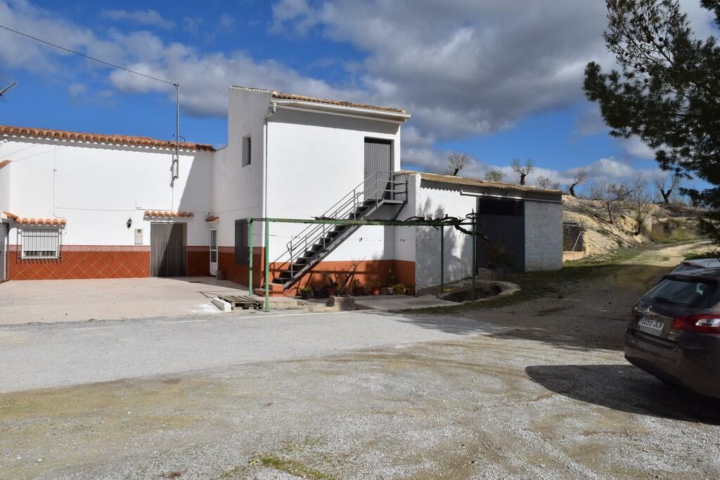 Cave house with white exterior walls and outdoor staircase in Cuevas del Campo, Granada. Scenic rura.