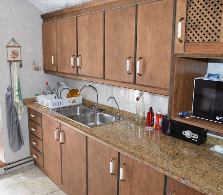 Charming cave house kitchen with wooden cabinets and modern appliances in Cuevas del Campo, Granada.