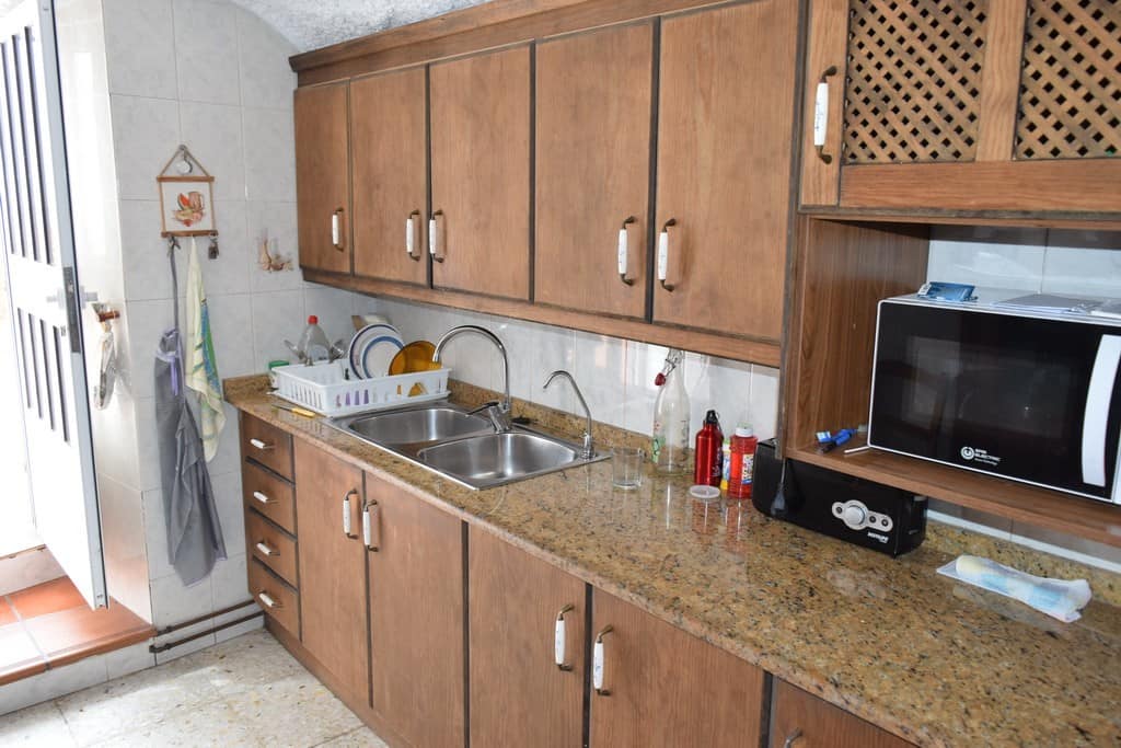 Charming cave house kitchen with wooden cabinets and modern appliances in Cuevas del Campo, Granada.