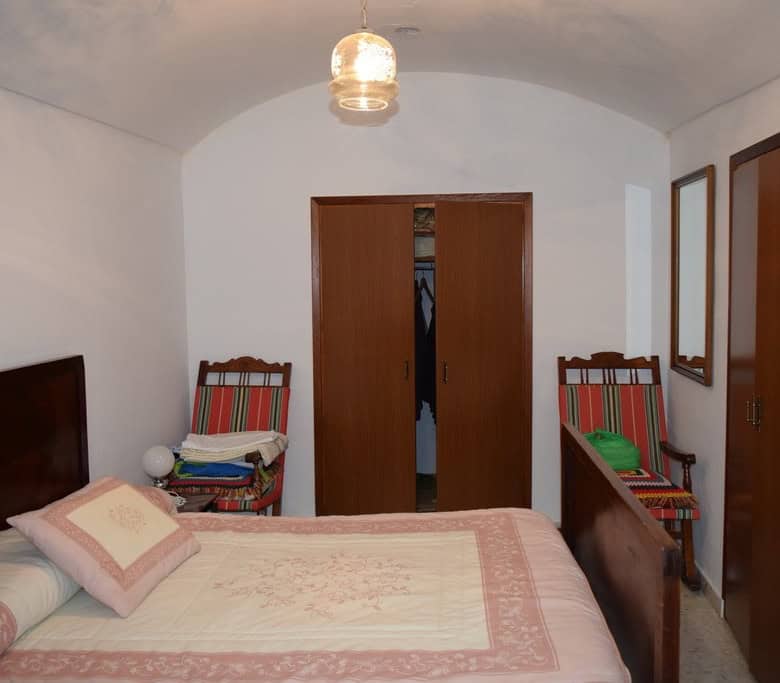 Cave house bedroom with traditional decor in Cuevas del Campo, Granada, featuring wooden furniture a.