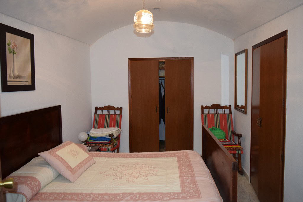Cave house bedroom with traditional decor in Cuevas del Campo, Granada, featuring wooden furniture a.
