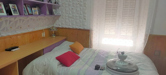 Bright bedroom with colorful pillows and wooden accents in a village property in Benamaurel, Granada.