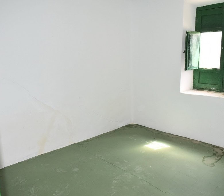 Traditional Spanish room with green window shutters and white walls.