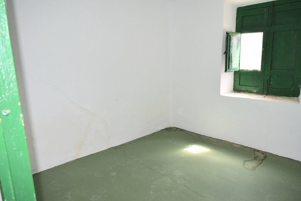 Traditional Spanish room with green window shutters and white walls.