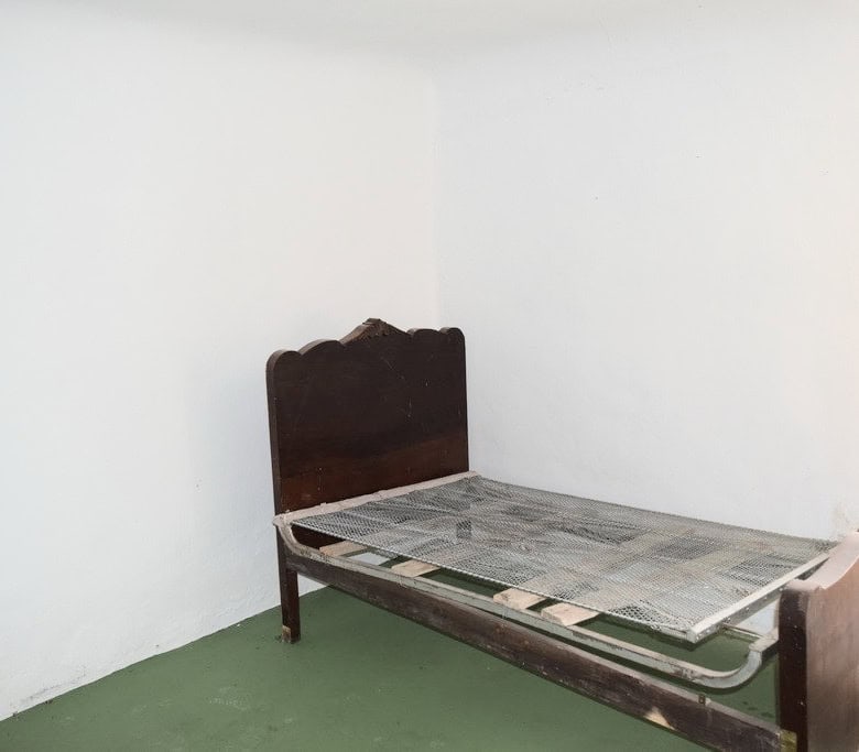 Rustic bedroom with vintage wooden bed frame in Benamaurel, Granada.